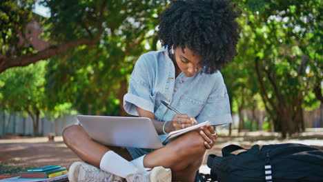 girl laptop making notes in notepad sitting nature close up. student studying