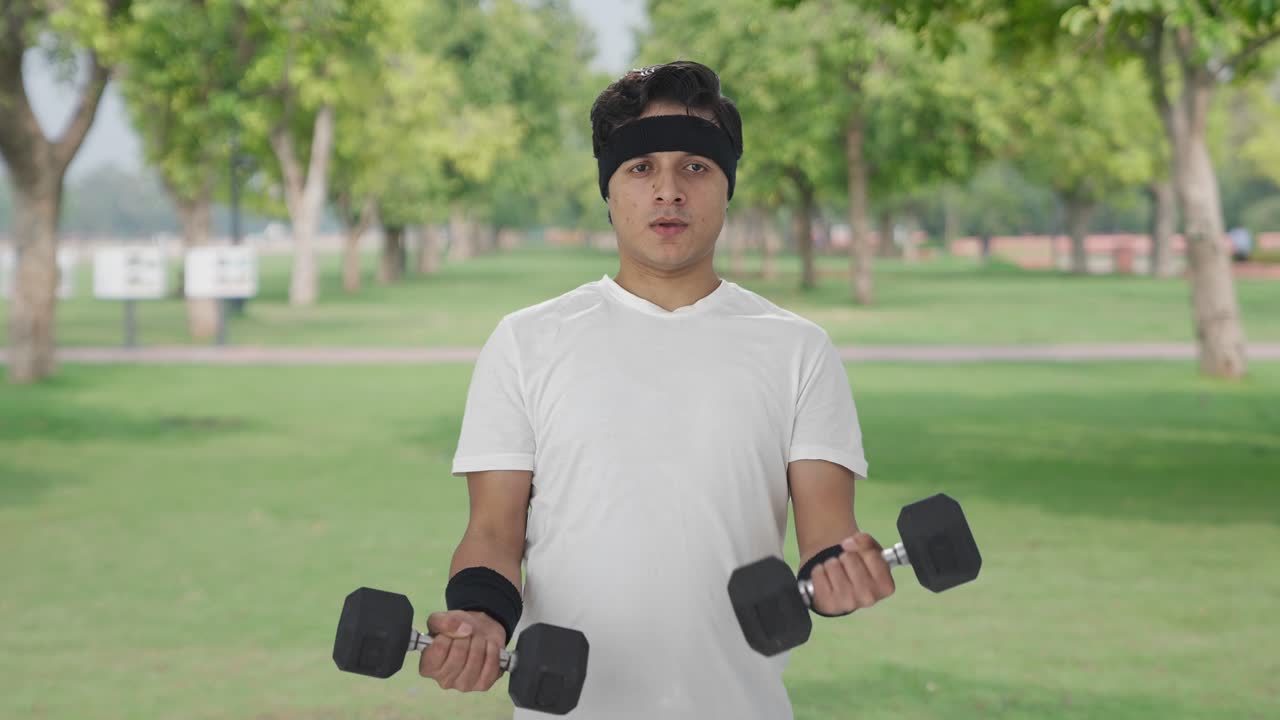 무거운 덤벨을 들어 올리는 심각한 인도인