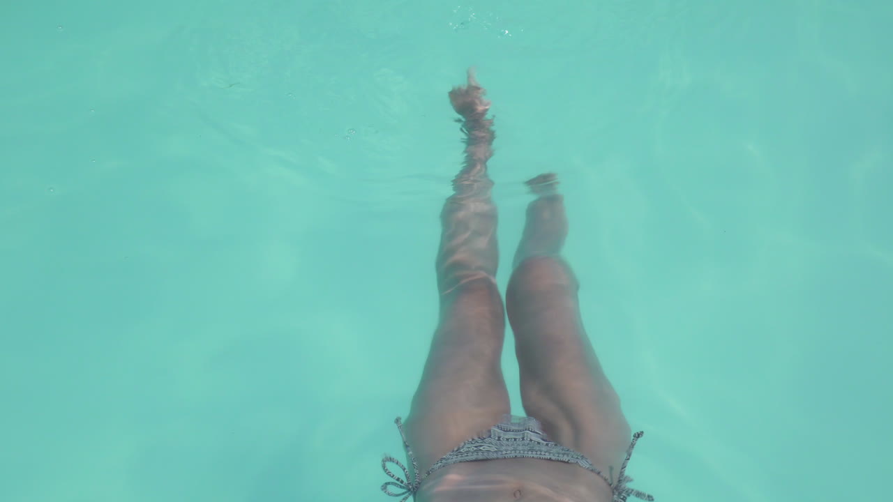 Donna che si rilassa e muove i piedi in una piscina all'aperto