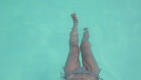 Woman-relaxing-and-paddling-her-feet-in-outdoor-swimming-pool