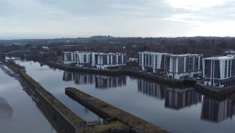 Early-morning-aerial-view-riverside-waterfront-contemporary-apartment-office-buildings-canal-regeneration-real-estate-reverse-right-orbit