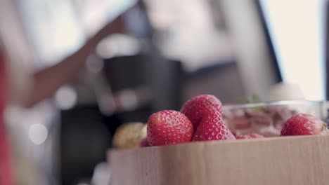 Cerca-De-Fresas-Mientras-Una-Mujer-Prepara-Café-En-El-Fondo