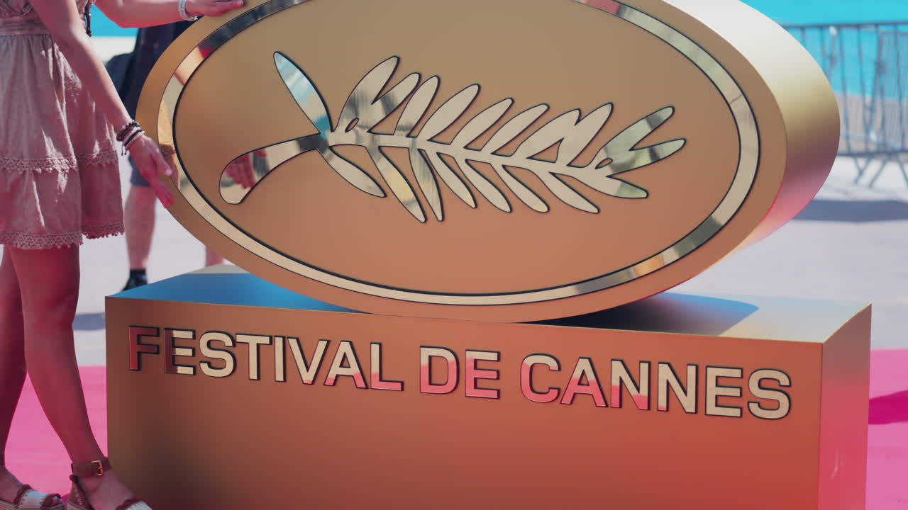 Cannes, France - May 13, 2025: Woman posing with the Cannes Film Festival golden sign
