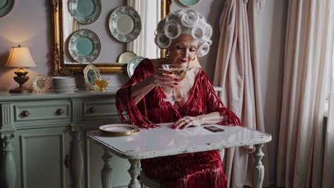 senior woman enjoying elegant cocktail moment, wearing red dress and sitting in vintage dining room, exuding sophisticated charm and peaceful contentment