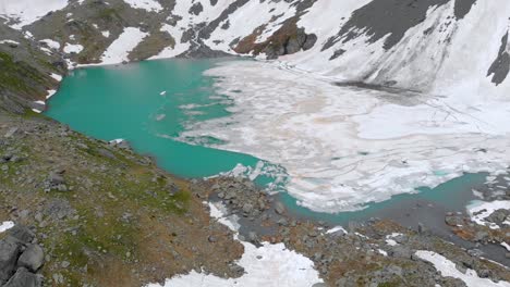 drone shot of a frozen white lake in the alps near grenoble with turquoise water and icebergs floating