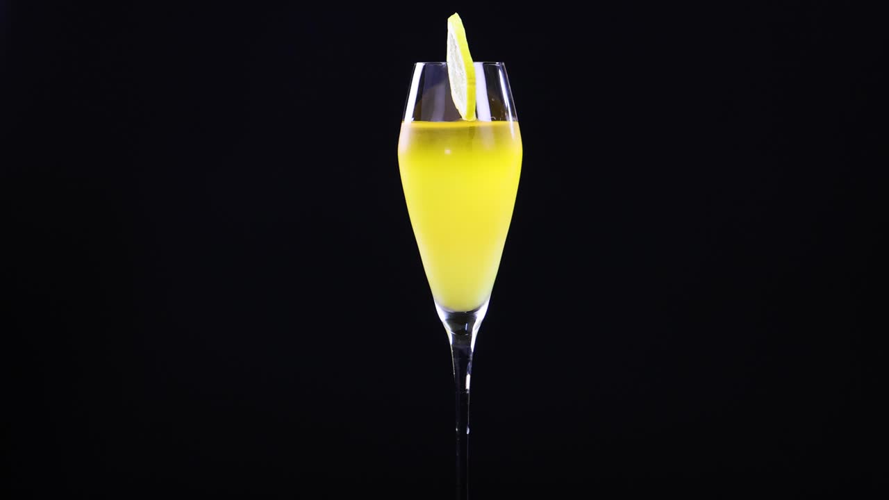 A lemon sour cocktail in a glass with a lemon slice garnish, set against a black background