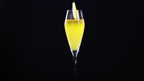 a lemon sour cocktail in a glass with a lemon slice garnish, set against a black background