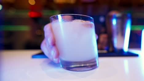 close-up of a bartender's hand bringing a finished drink towards the camera in slow motion