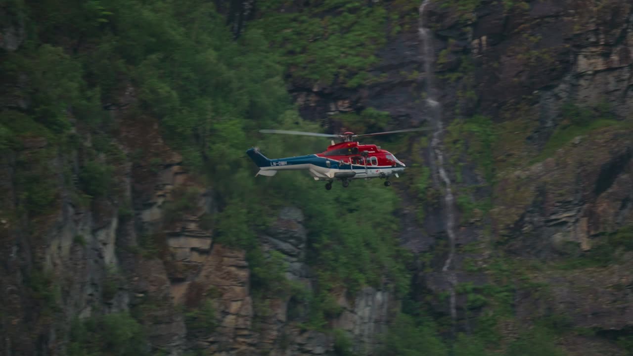Helikopter flyver nær stejle klipper i Geiranger Fjord, Norge. Redningsmission
