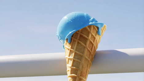 blue ice cream cone melting against a bright sky