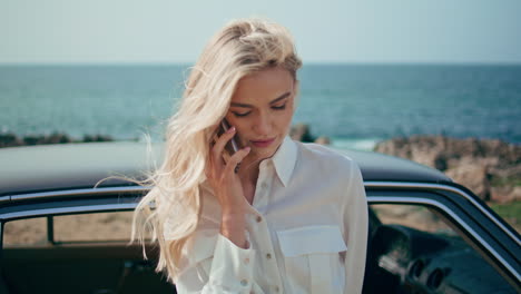 attractive girl calling shore standing near retro car closeup. woman using phone