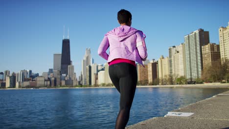 african american female running by shoreline with headphones