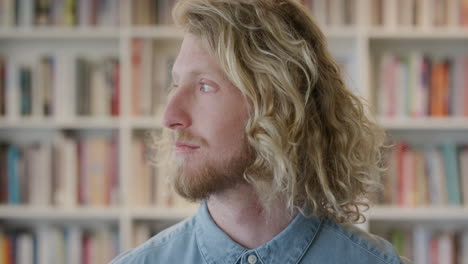 Porträt-Eines-Jungen-Blonden-Studenten,-Der-Ruhig-Lächelt-Und-Nachdenklich-Aus-Dem-Fenster-Im-Hintergrund-Der-Bibliothek-In-Zeitlupe-Schaut