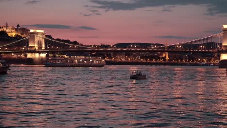 Have a look at the Szechenyi Bridge from Buda to Pest side from the river. Few boats are floating on the river Danube just before sunset