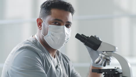 Portrait-of-Male-Doctor-in-Mask-Using-Microscope