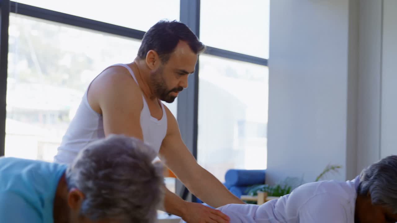 entrenador ayudando a las mujeres mayores en la realización de yoga 4k