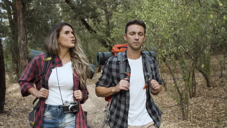 happy couple of active travelers walking across the forest