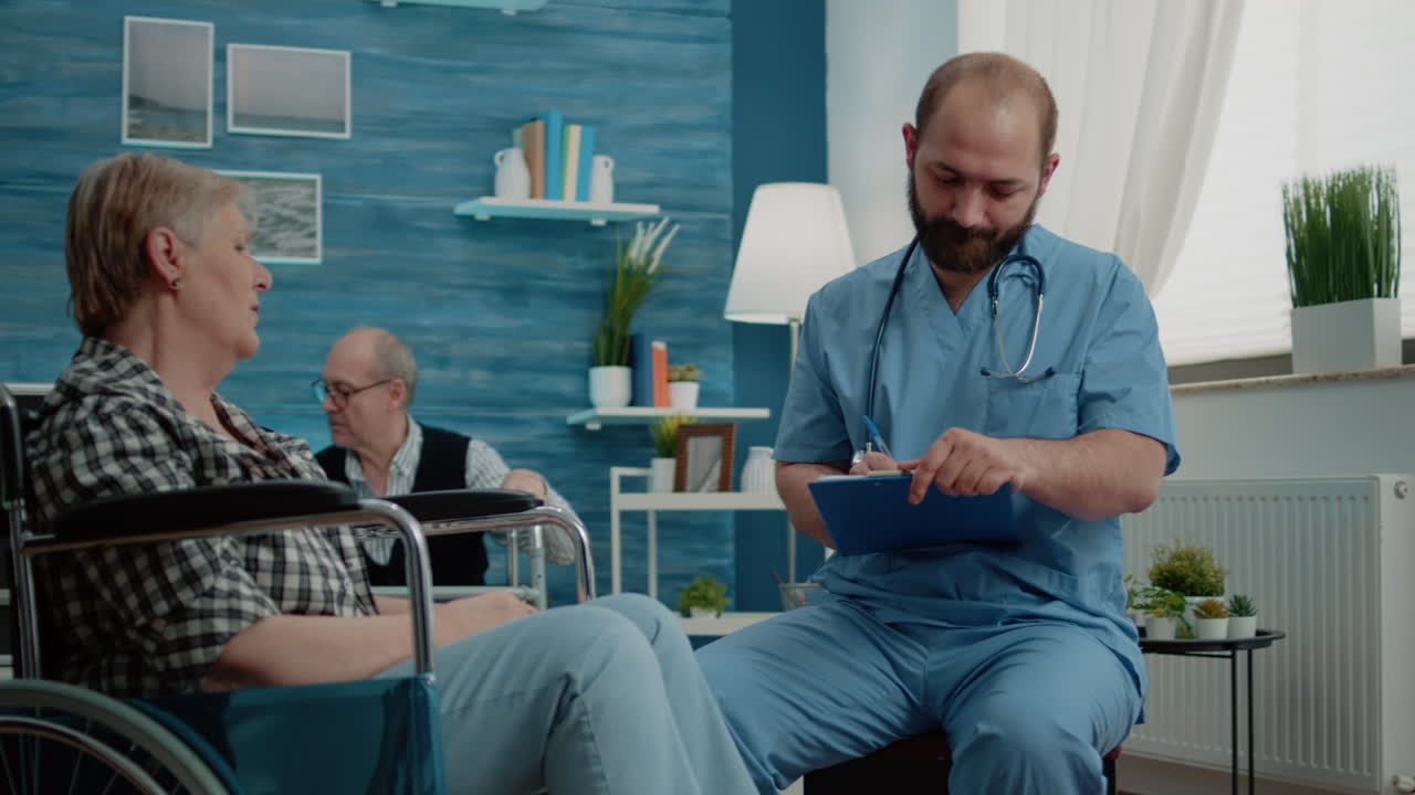 Man nurse consulting elder woman with disability in nursing home