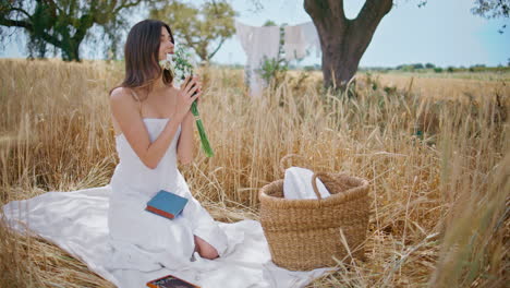 sensual girl sniffing flowers on summer picnic. lady taking bouquet from basket