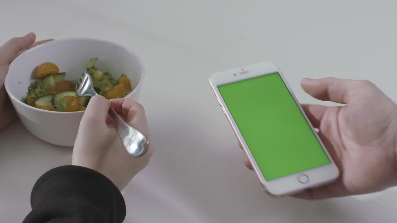 comiendo ensalada y usando un teléfono inteligente