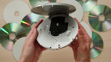 hands holding a portable cd player with cds