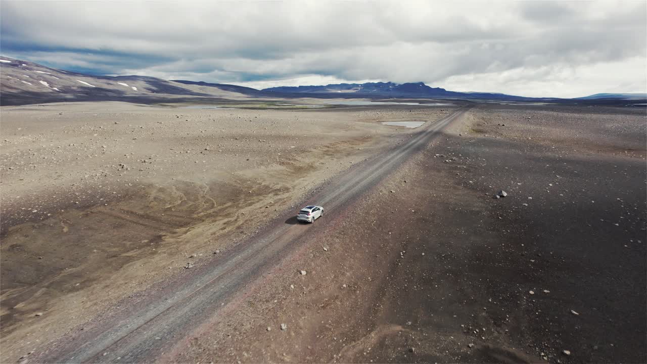 dron siguiendo un automóvil plateado que conduce fuera de la carretera en el campo lunar de islandia en 4k