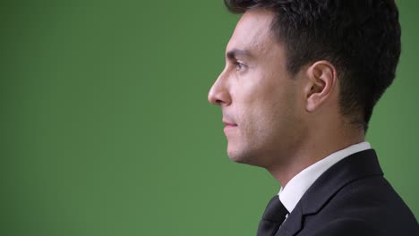 young handsome hispanic businessman against green background