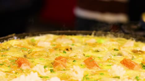 Close-up of a seafood omelette cooking, showcasing vibrant ingredients and steam rising from the pan.