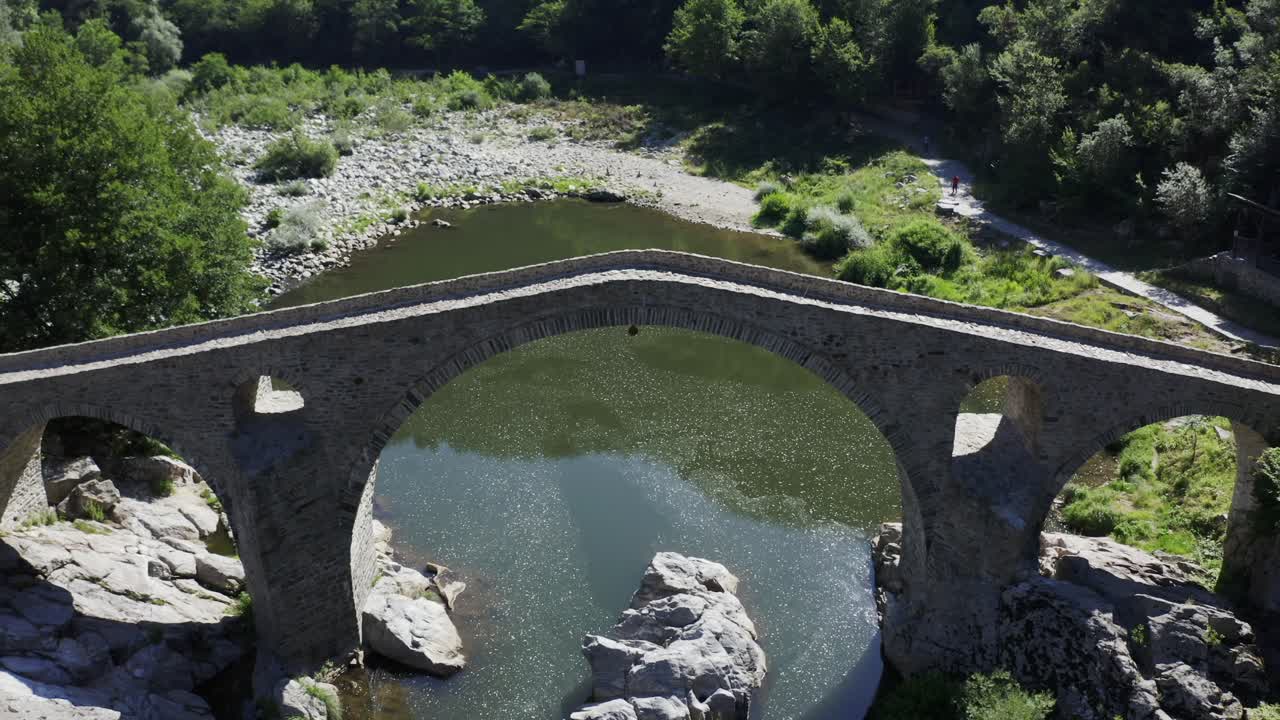 Tilting drone shot revealing the front view of the Devil's Bridge located in Ardino at the foot of Rhodope Mountain in Bulgaria