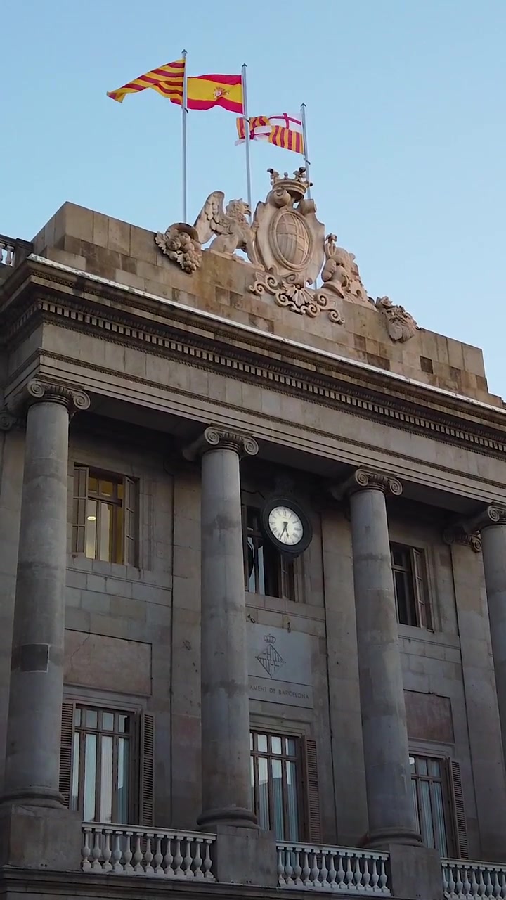 Vista verticale del Consiglio Comunale di Barcellona, un edificio neoclassico che espone le bandiere di Spagna e Barcellona, in Piazza Sant Jaume