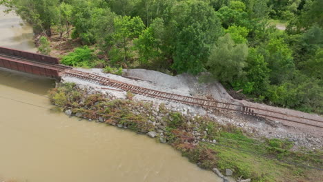 high aerial orbit view: damaged railroad tracks over eroded ground in vermont, post-2023 historic flooding