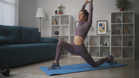 Una-Mujer-Practica-Yoga-En-Casa-Realizando-Asanas-En-El-Suelo-De-La-Sala-De-Estar-Por-La-Mañana-Estirando-La-Postura-Del-Guerrero-Del-Entrenamiento