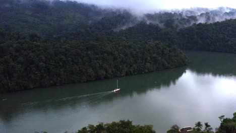 luxury yacht sails alone along river reflecting the nature and mist above
