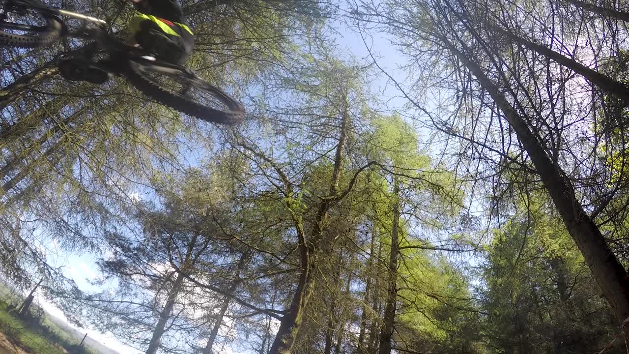 cámara lenta, ciclistas de montaña montando en pista forestal, saltando sobre la cámara