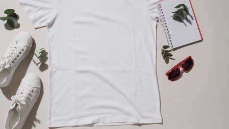 Video-of-flat-lay-of-white-t-shirt,-sneakers,-sunglasses-and-copy-space-on-white-background