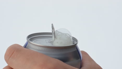 closeup man hand open can of beer in super slow motion. bubbling foam spilling.