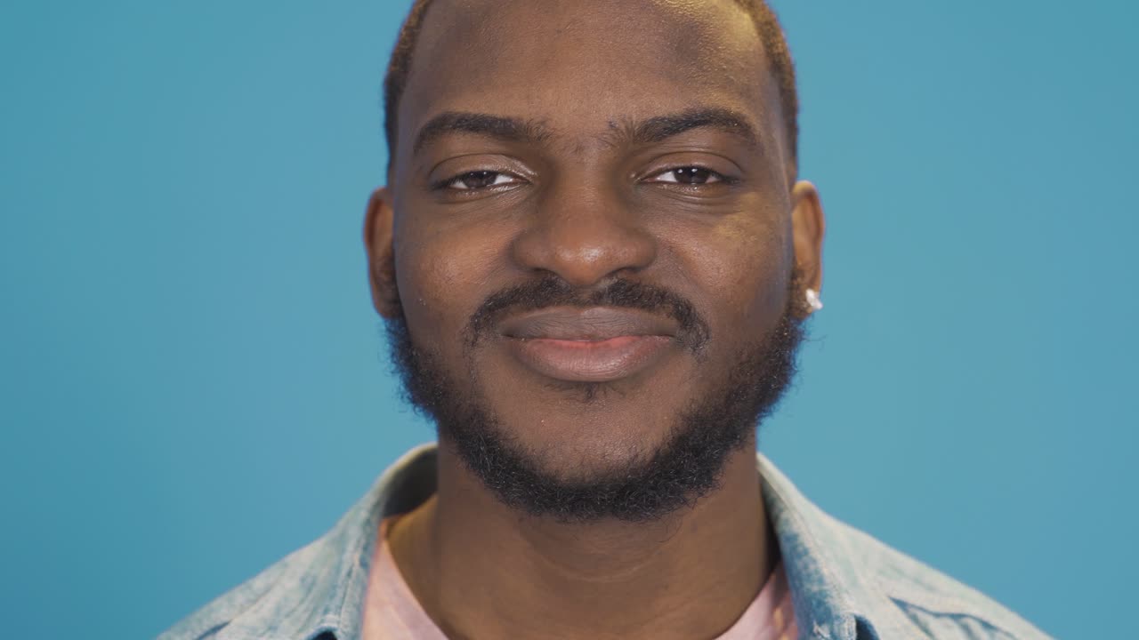un joven negro feliz y positivo sonriendo, mirando a la cámara.