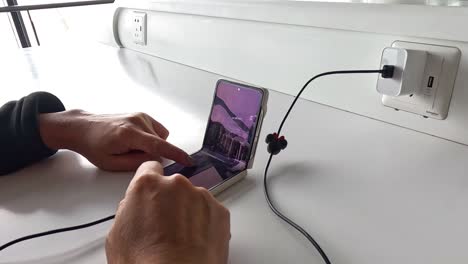 persona que utiliza un teléfono inteligente conectado a un cargador
