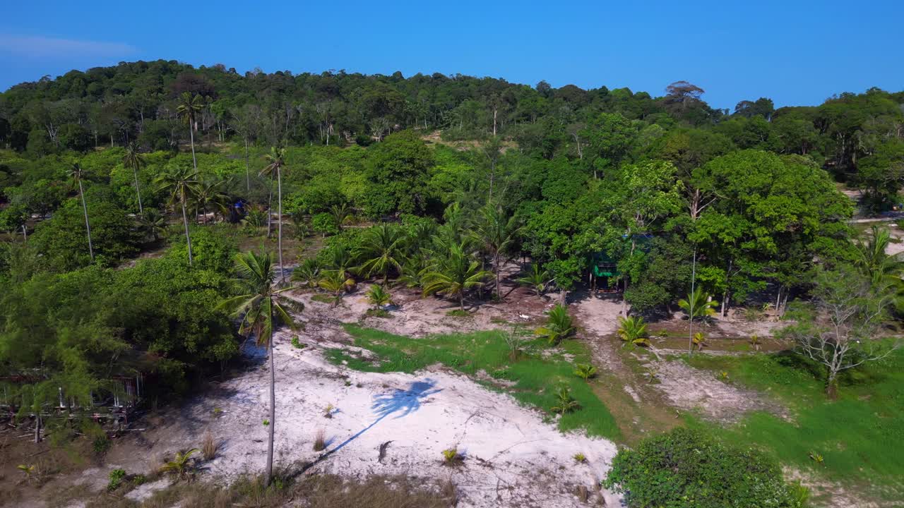 Tropical landscape showing turquoise sea washing white sand beach and green rainforest covering Koh Rong island in Cambodia. Best aerial view flight fly reverse drone