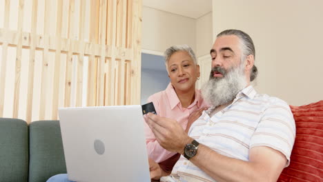 senior couple using laptop and holding credit card, shopping online together