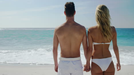 Couple-holding-hands-while-looking-at-the-beach