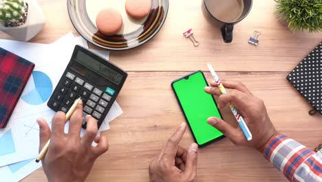 mano usando teléfono inteligente y calculadora en la mesa, de arriba hacia abajo
