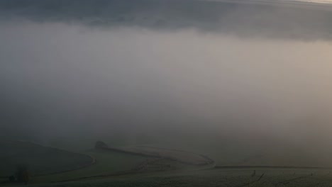 soft sunlight filters through a thick blanket of fog, creating a serene and ethereal atmosphere over the landscape, evoking a sense of peace and tranquility