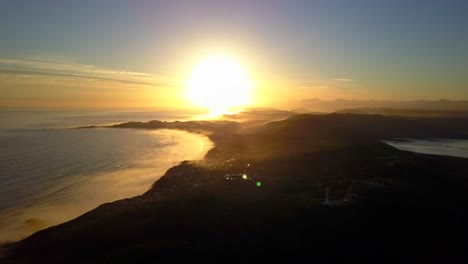 Golden-Hour-Sunset-over-South-African-Coast,-Aerial-Drone-Backward-Motion-with-Lens-Glare