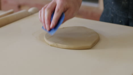 handheld close up shot of scraping a piece of flat clay