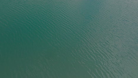 4K-fly-forward-shot-across-a-sapphire-blue-Himalayan-glacial-lake-revealing-snow-capped-peaks