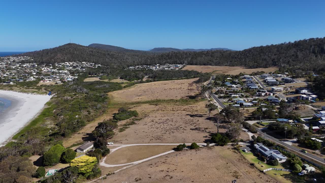 Dry land near the seaside and suburban neighborhood during daytime, aerial shot