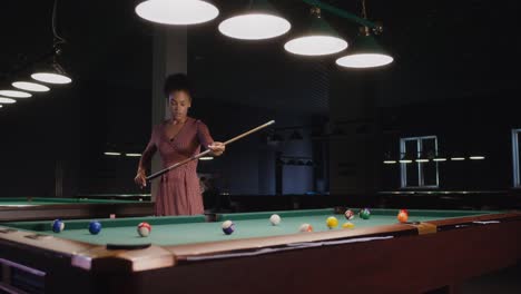 woman playing pool in a dark billiards room
