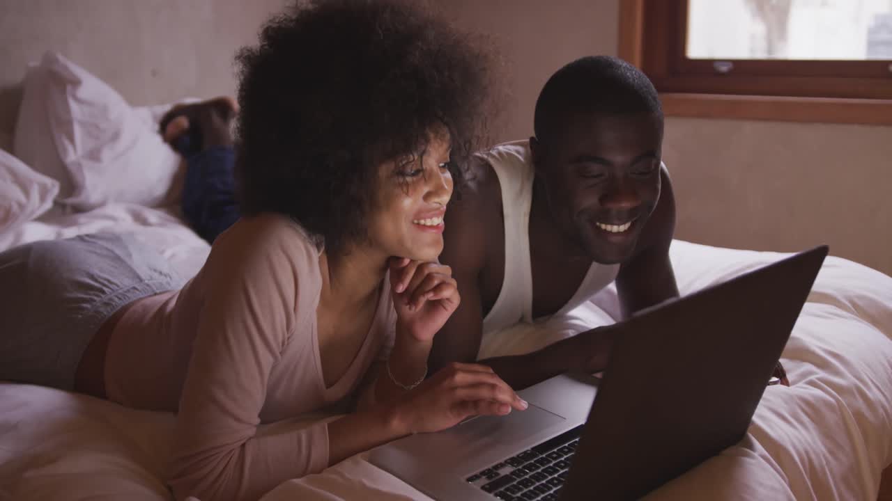 Couple using computer in bedroom at home
