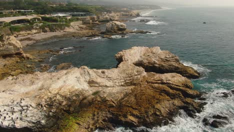 Tiro-De-Drone-De-Una-Enorme-Formación-Rocosa-Frente-A-La-Playa-De-Newport,-Ca